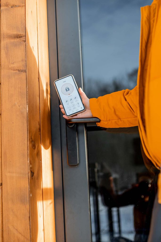 woman locking smart lock with phone on the entrance